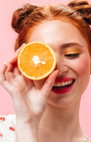 young energetic red haired woman white t-shirt 
                holding tasty orange